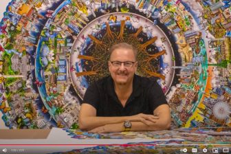 Fazzino sitting in front of his very large circle of life 3d pop artwork