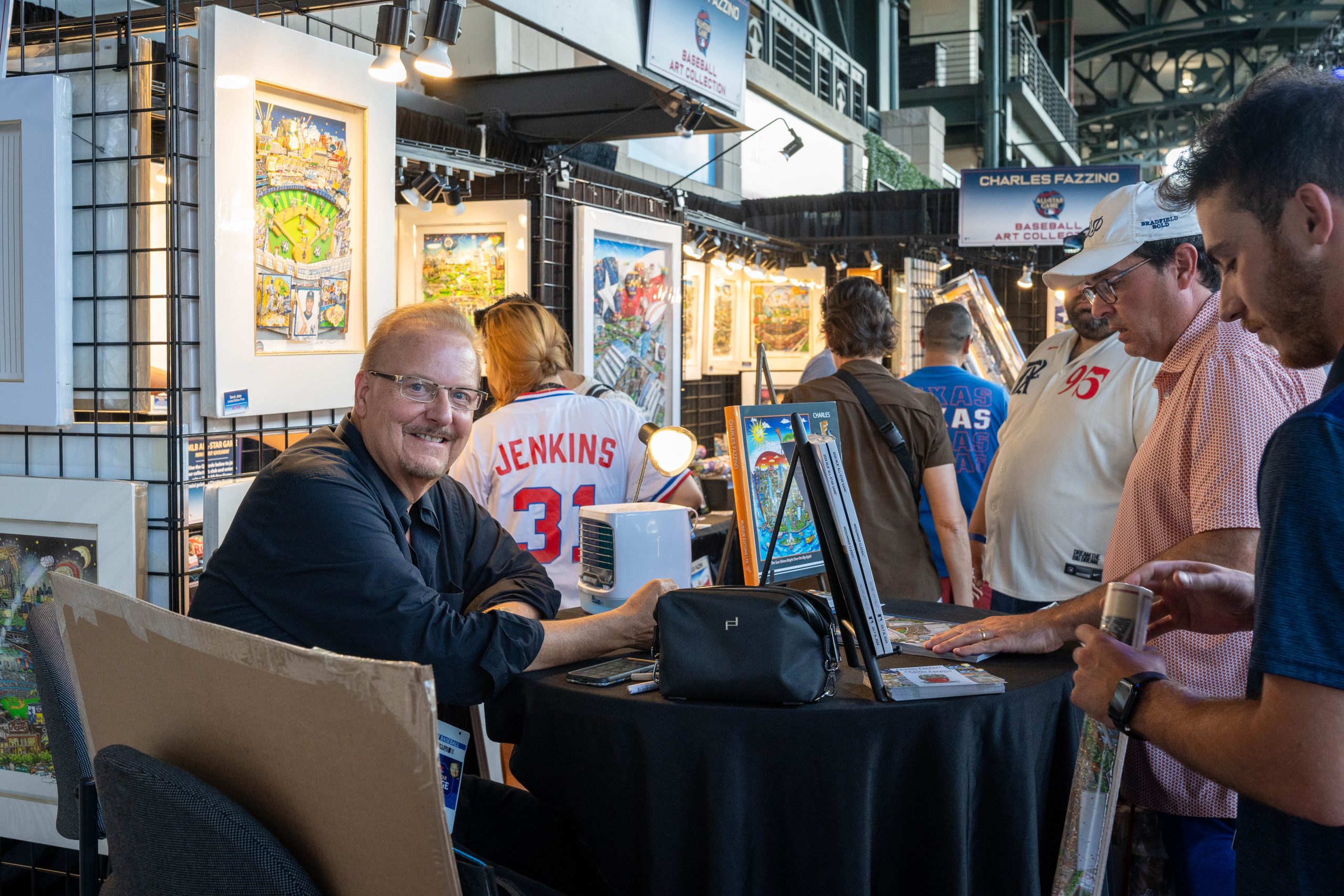 Fazzino turns to the camera to smile while signing posters for fans at the All-Star Game