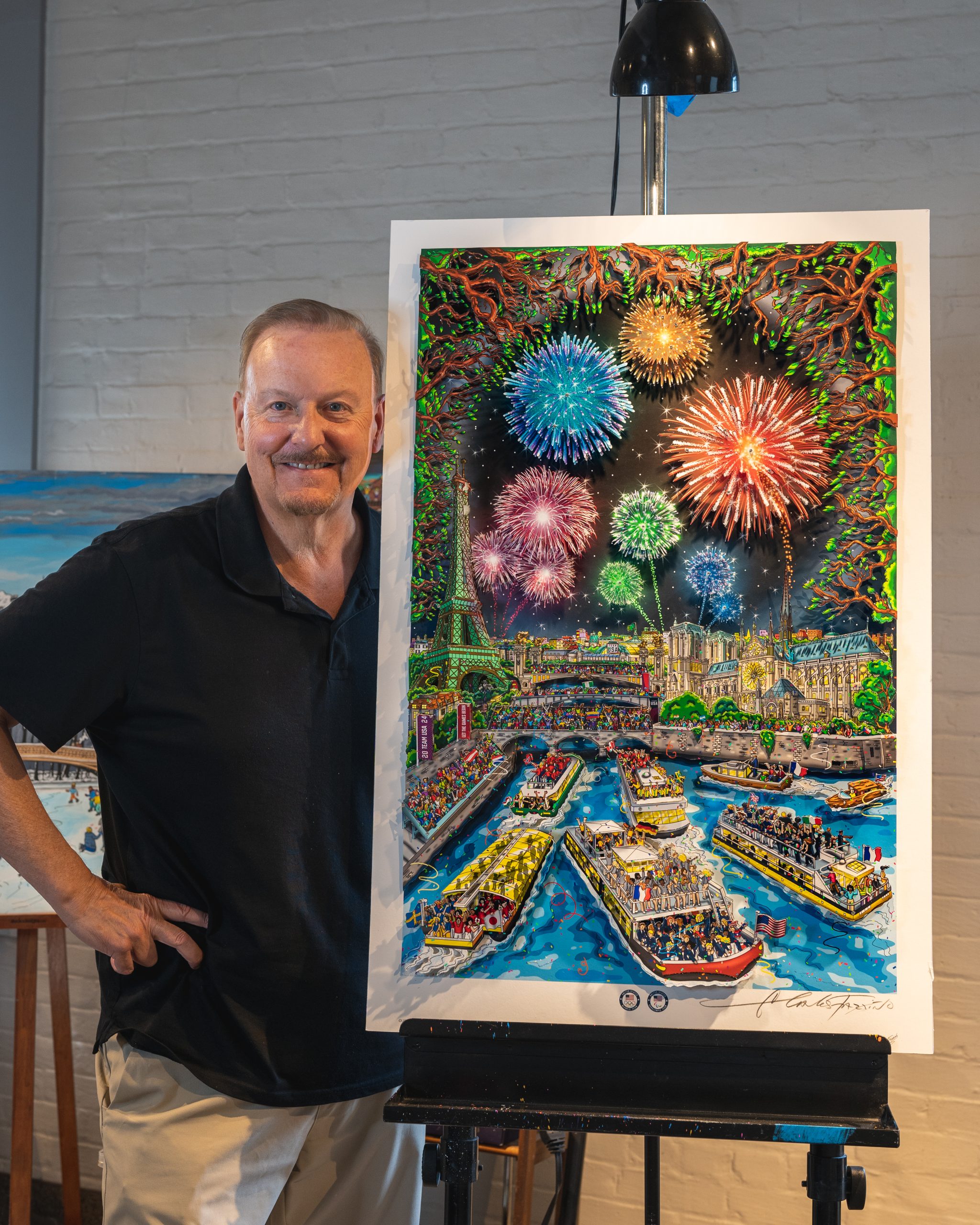 Fazzino stands next to his 2024 Paris Olympics artwork, the piece filled with boats in the Seine River and fireworks above the Eiffel Tower