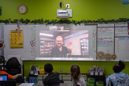 Fazzino on a projector on a video call talks to STEM students in the classroom