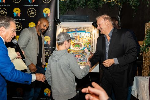 Charles Fazzino, David Tyree, and Bruce Beck shaking hands with one of the auction winners of Fazzino's commemorative artwork.