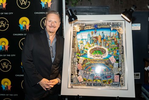 Fazzino smiles as he stands next to his commemorative artwork that is colorful and and jam packed with Giants history and the New York cityscape