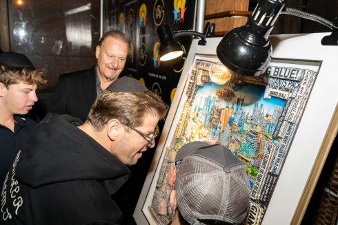 The auction winners taking a close look at the commemorative artwork full of Giants history while Fazzino smiles in the background