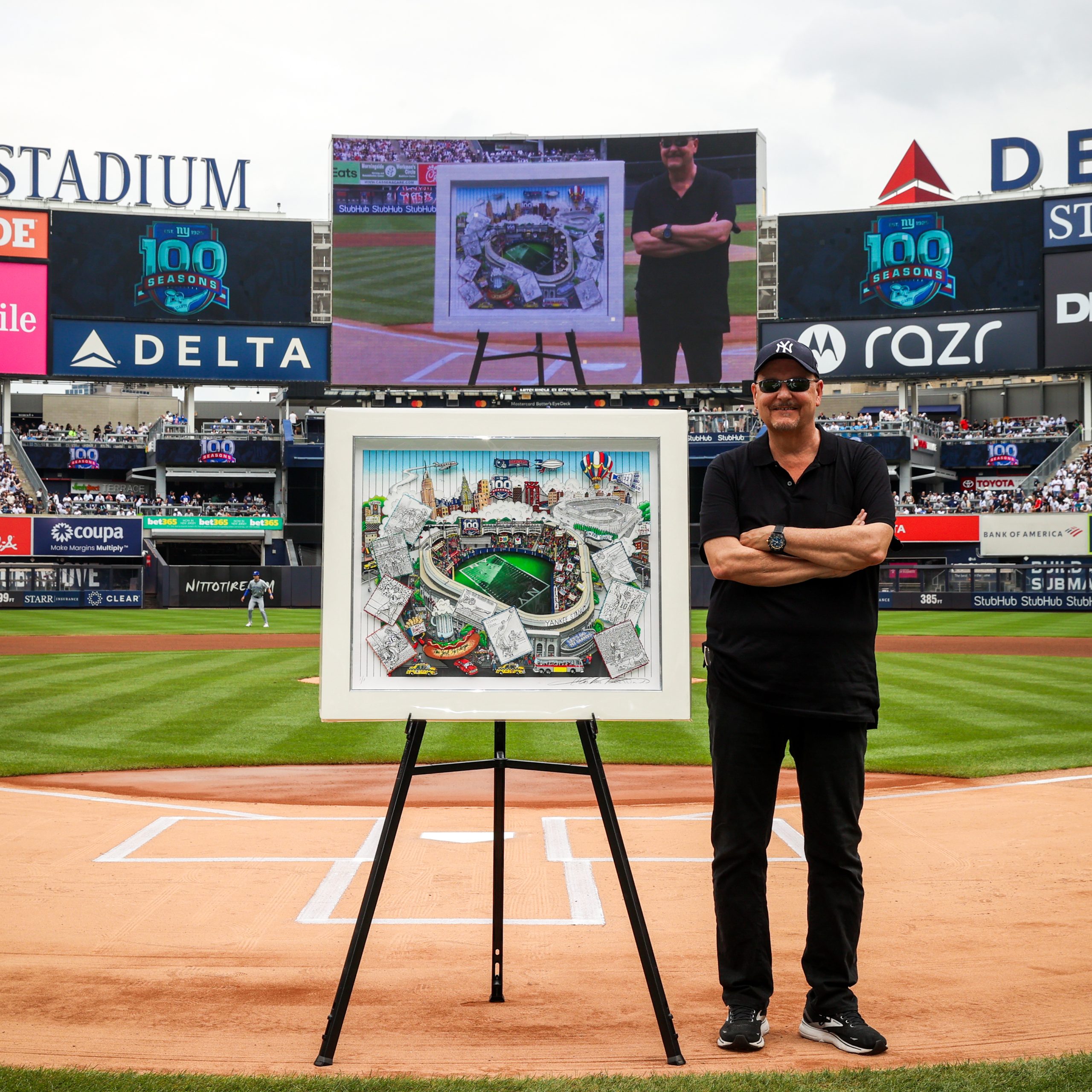 Fazzino stands on the field at Yankee Stadium next to his artwork that is being unveiled for the Giants 100th Anniversary