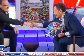 Fazzino shakes Brian Kilmeade's hand after presenting him with a one-of-a-kind 3D helmet to celebrate Super Bowl LIX